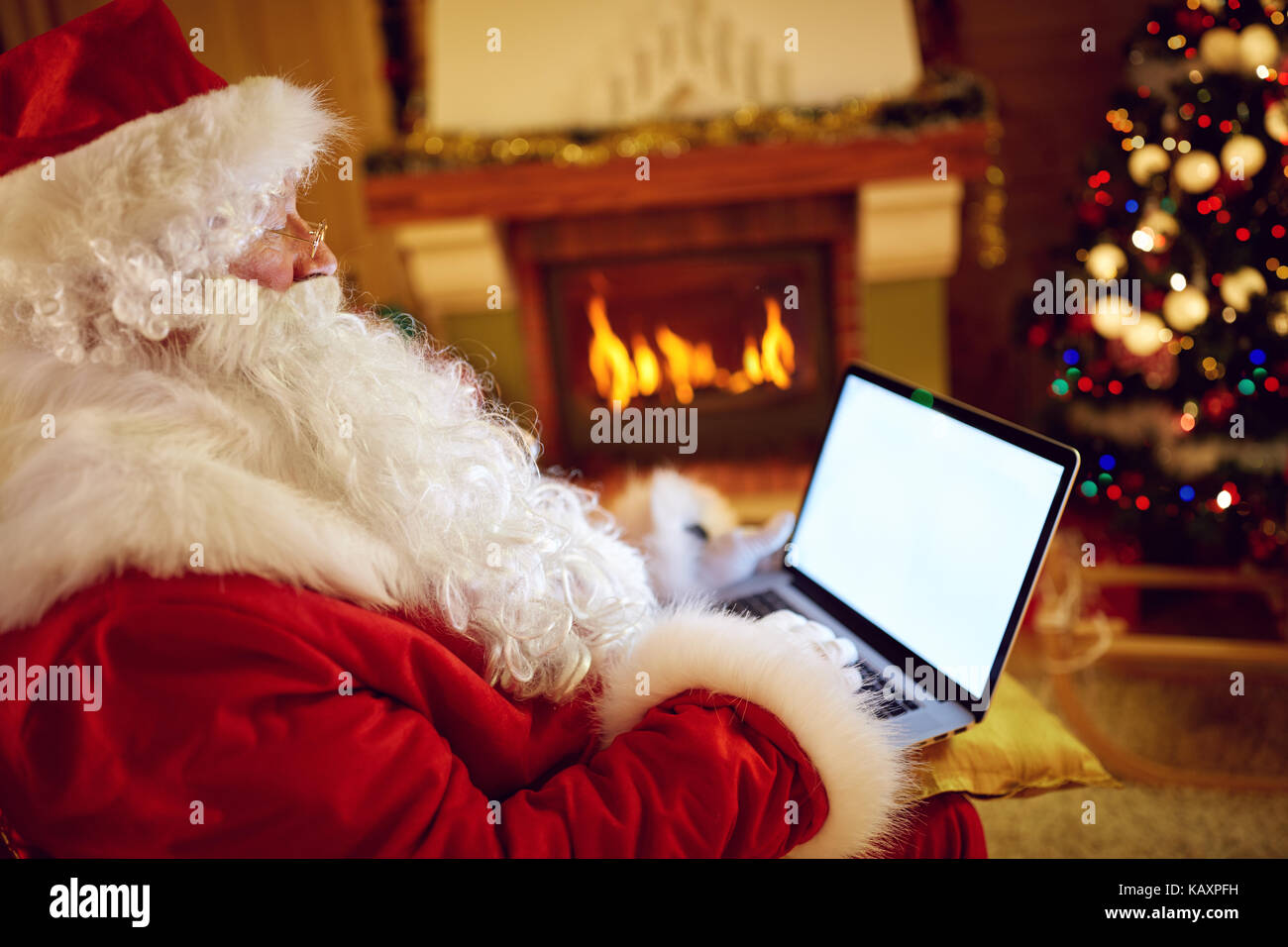 Babbo Natale la lettura di messaggi di posta elettronica sul computer portatile con il natale la richiesta o la lista dei desideri Foto Stock