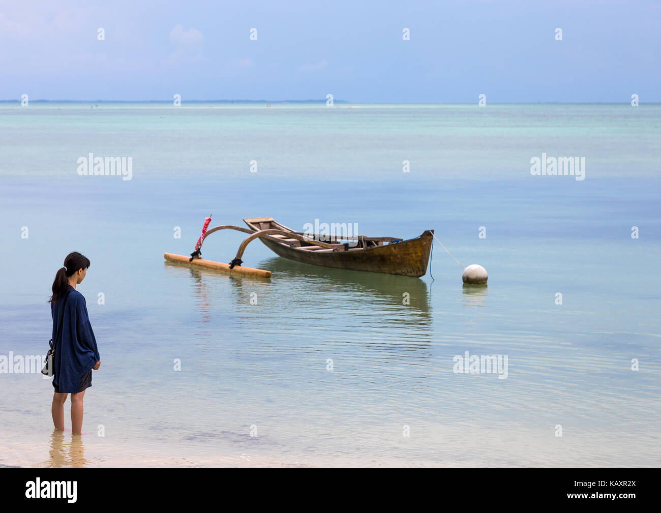 Japanses donna di fronte a una barca sulla costa, isole yaeyama, Isola di Taketomi, Giappone Foto Stock