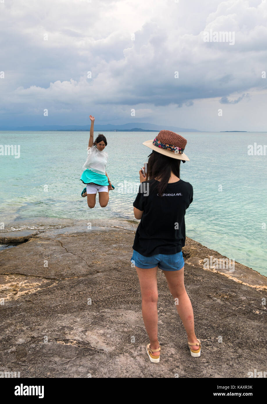 Turista giapponese salto per una foto sul molo di Nishi, isole yaeyama, Isola di Taketomi, Giappone Foto Stock