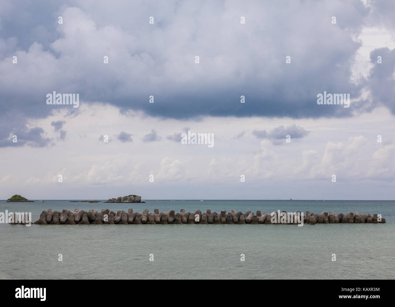 Calcestruzzo tetrapods lungo il porto al fine di assorbire la potenza delle onde che si infrangono contro le nuvole di tempesta, isole yaeyama, Isola di Taketomi, Giappone Foto Stock