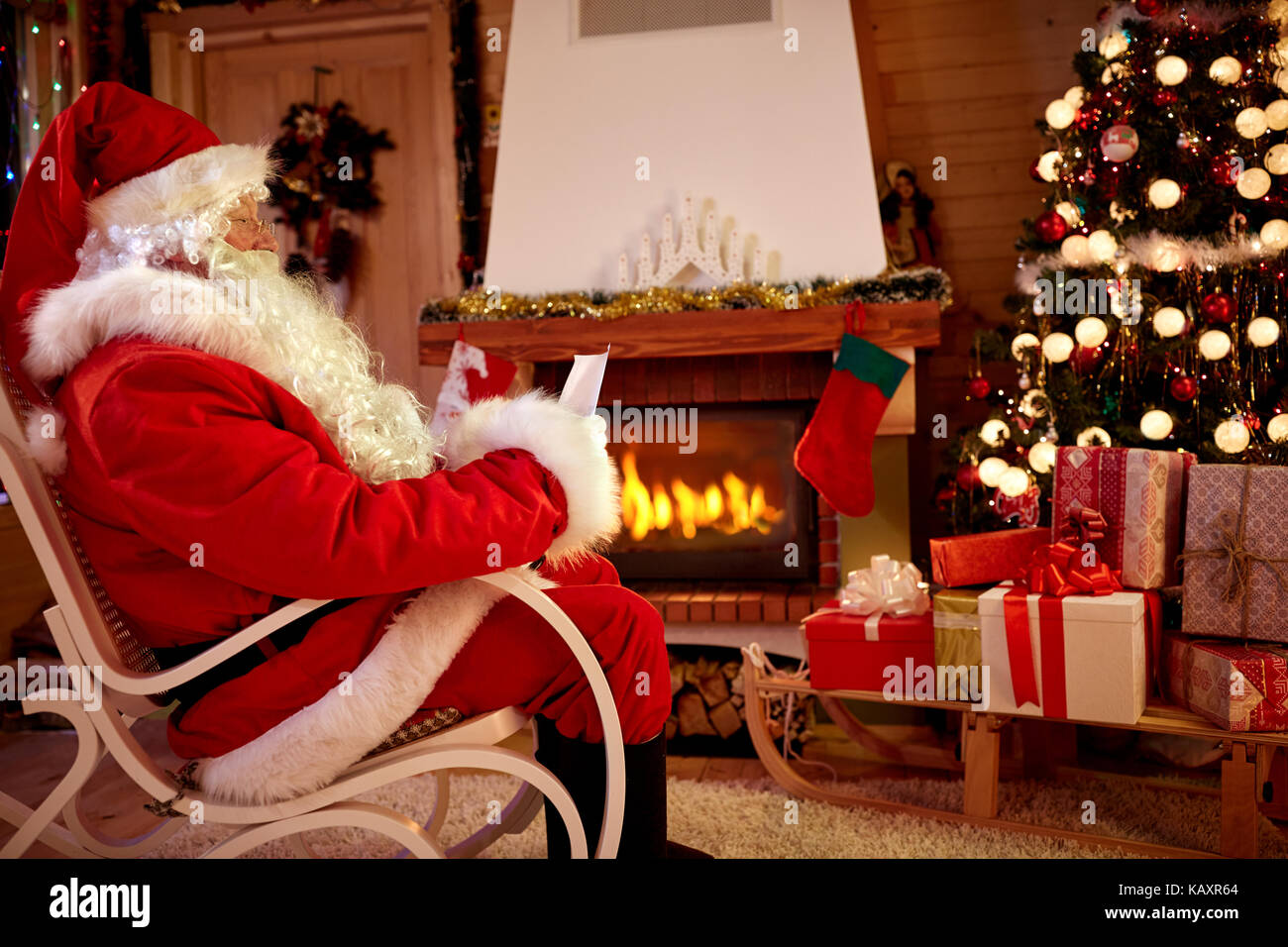 Santa Claus in camera vicino al camino letto bambini whishing list per il regalo di natale Foto Stock