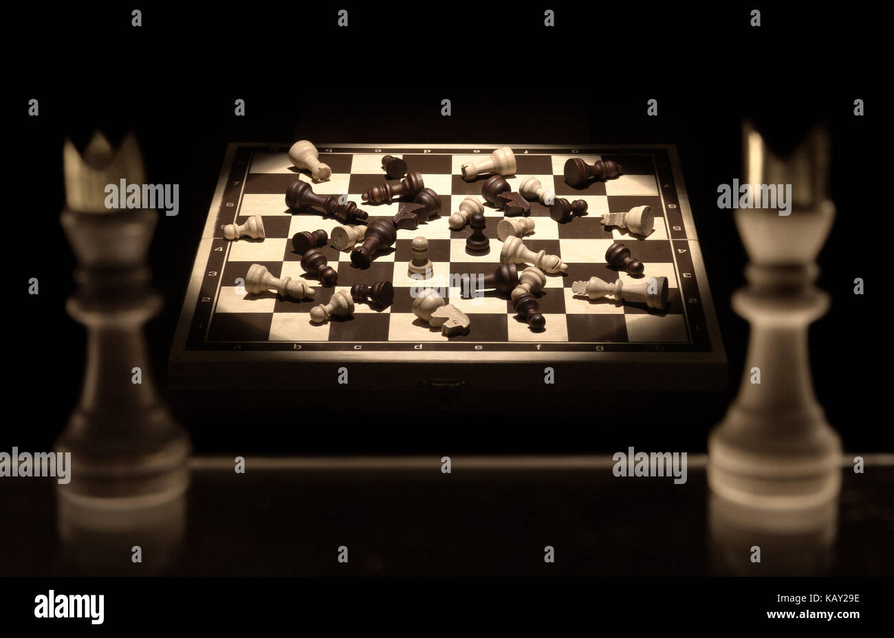 Scacchi re su uno sfondo nero cerca su una scacchiera completa del campo di battaglia di vittime come una metafora della natura della guerra Foto Stock