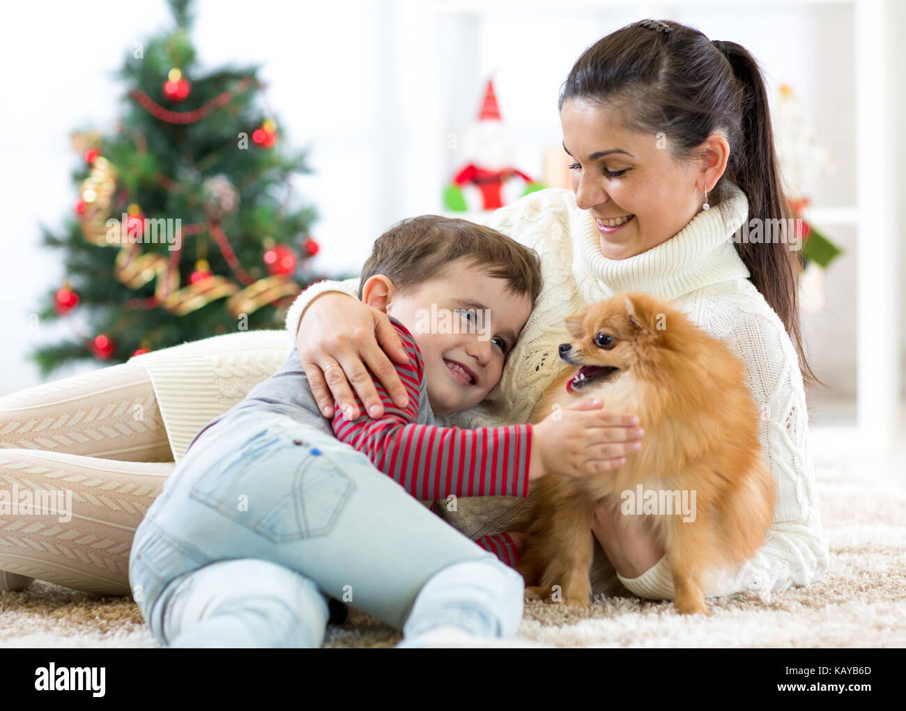 Madre di famiglia e suo figlio giocare con il cane a albero di natale Foto Stock