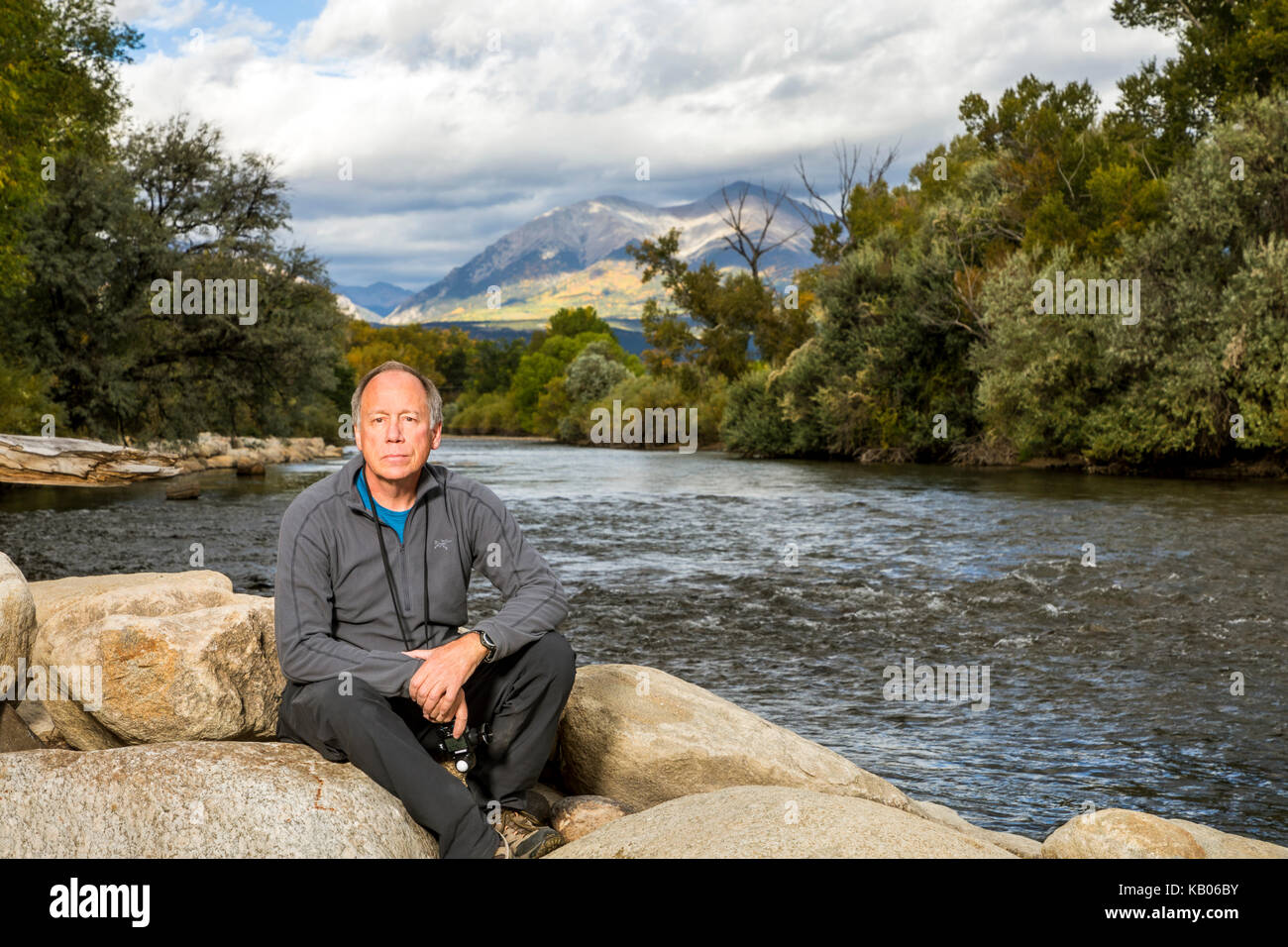 Ritratto di uomo seduto sulle rocce lungo il fiume Arkansas, Salida, Colorado, STATI UNITI D'AMERICA Foto Stock