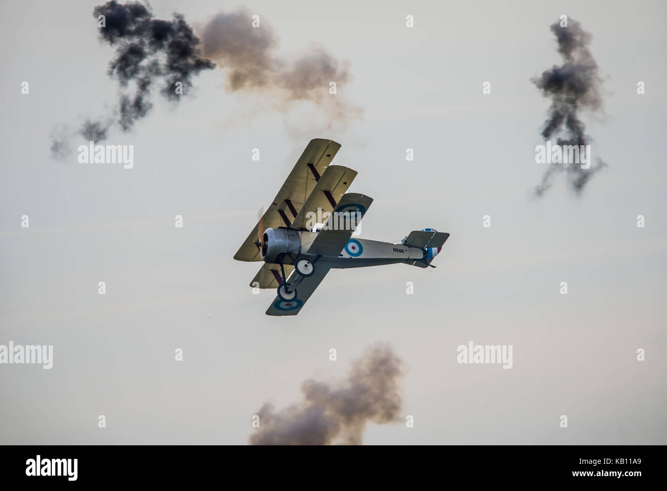 Sopwith Triplane del Great War display Team che vola attraverso raffiche di flack simulate all'IWM Duxford Airshow Foto Stock