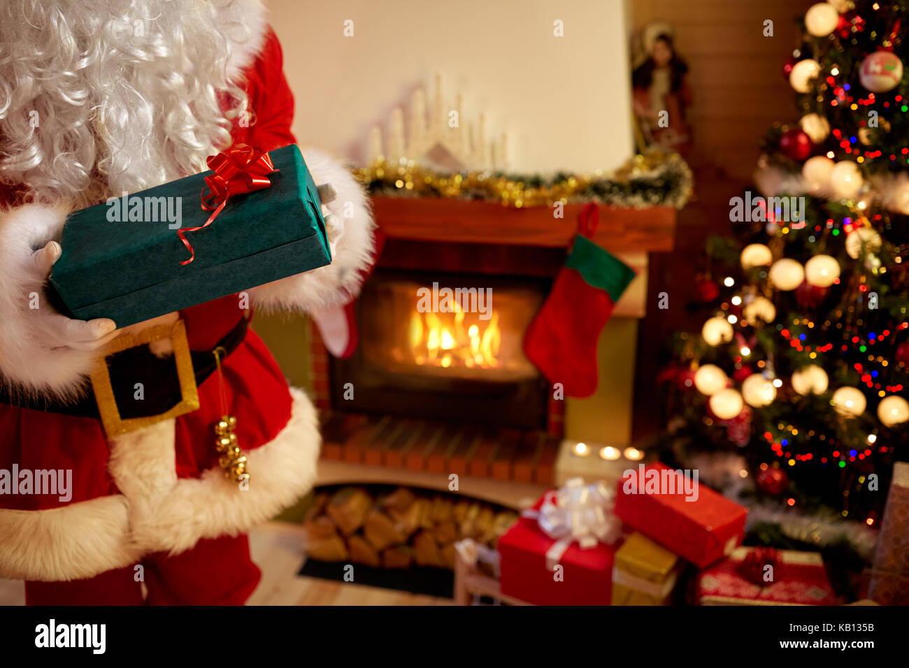 Santa Claus in mani guantate azienda confezione regalo accanto ad albero di natale Foto Stock