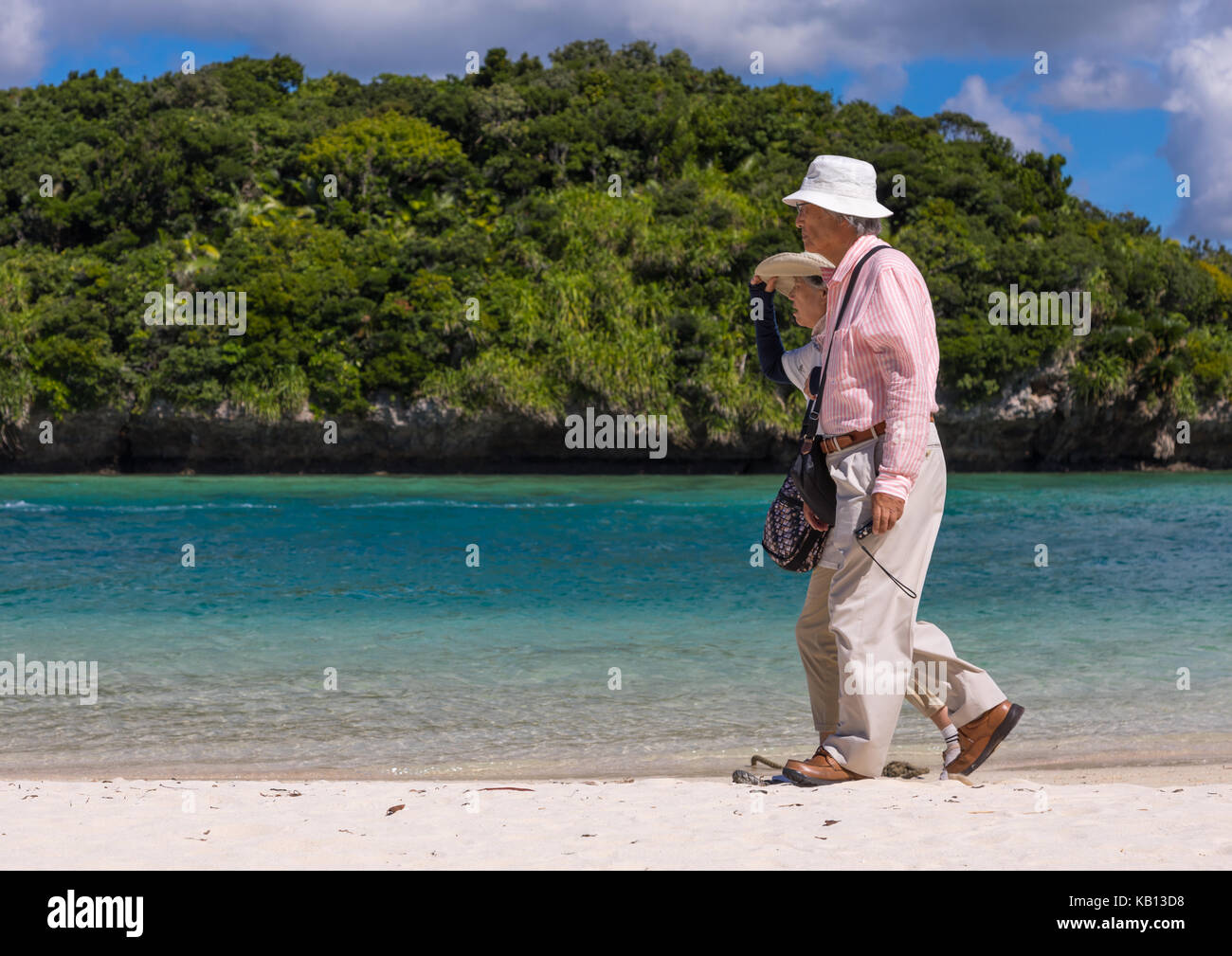 Vecchia coppia giapponese a piedi lungo la laguna tropicale con chiare acque blu nella baia di kabira, isole yaeyama, ishigaki, Giappone Foto Stock