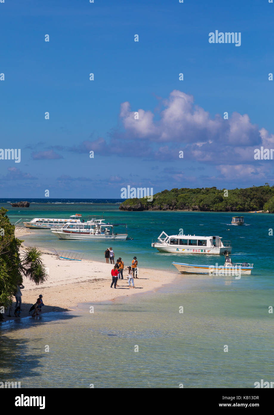 Barche con fondo di vetro nella laguna tropicale spiaggia con acque cristalline e la sabbia bianca circondata da una vegetazione lussureggiante di kabira bay, isole yaeyama, ishigaki, Giappone Foto Stock