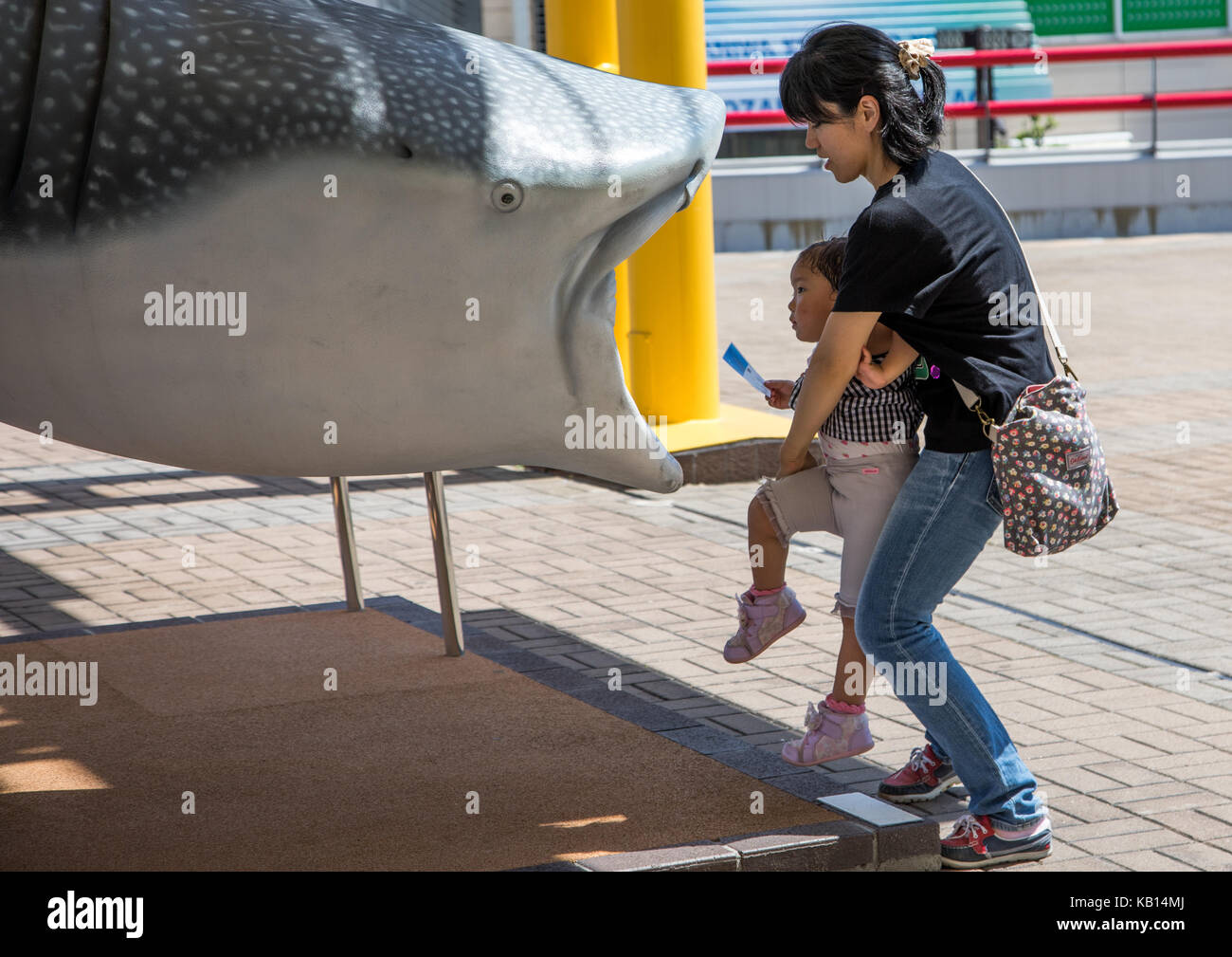 La madre tiene il bambino a lasciare il suo all'interno di un fake plastica gigante di squalo balena in Acquario Kaiyukan, la regione di Kansai di osaka, Giappone Foto Stock