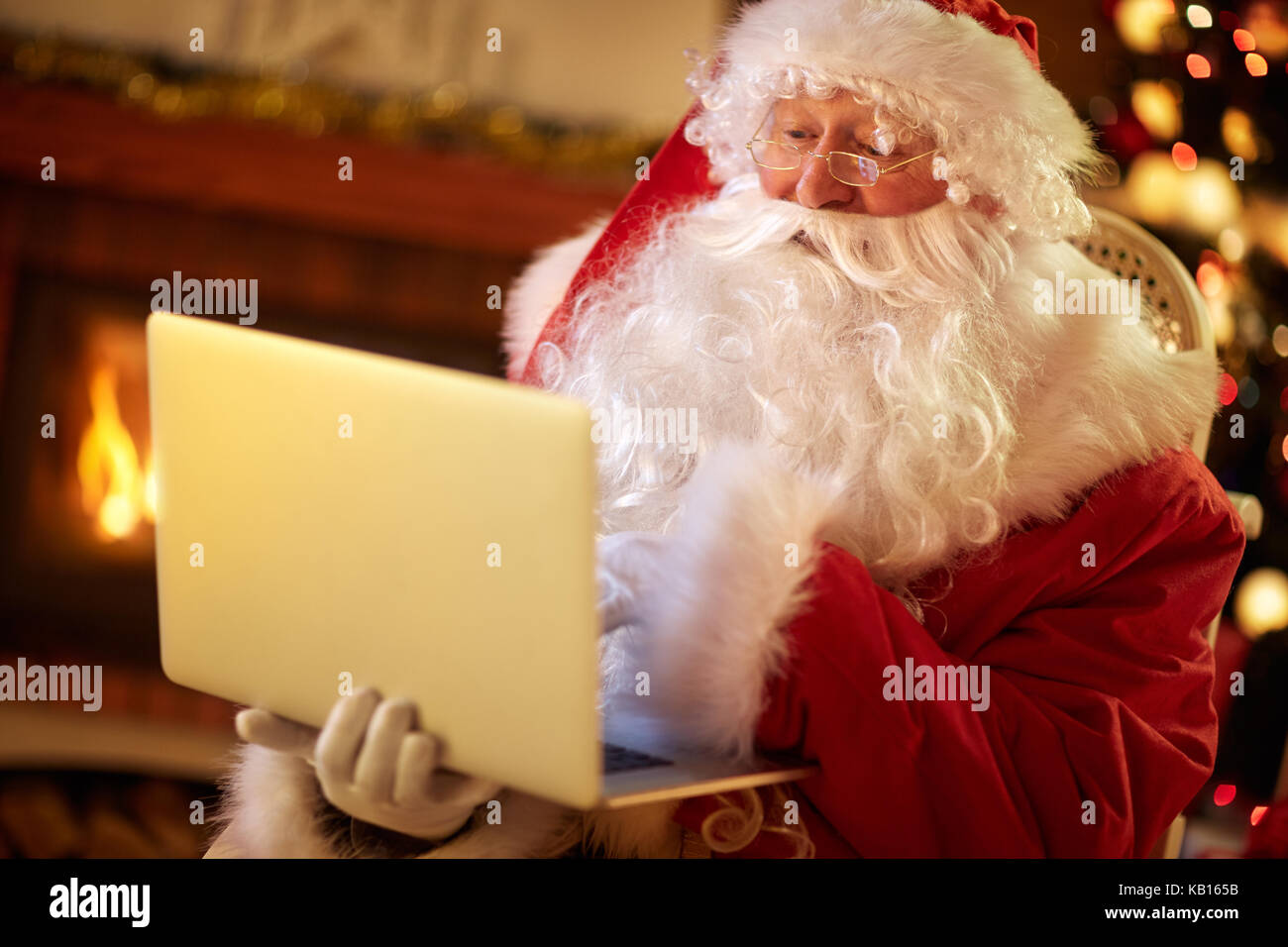 Babbo Natale seduto nel suo salotto e utilizzo di computer portatile Foto Stock