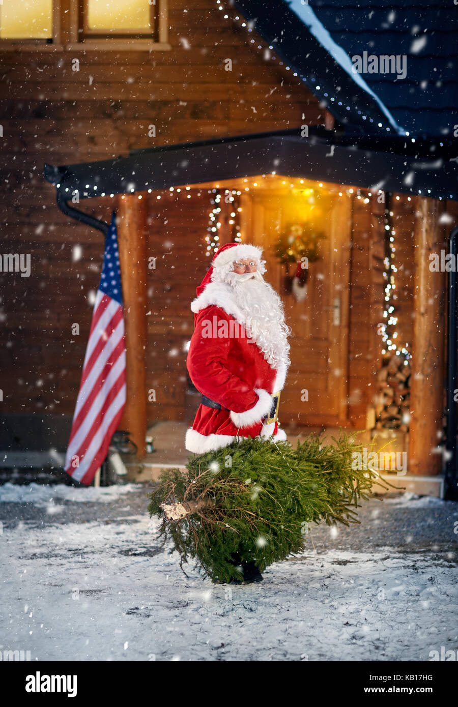 Babbo Natale porta un albero di natale in serata nevosa Foto Stock