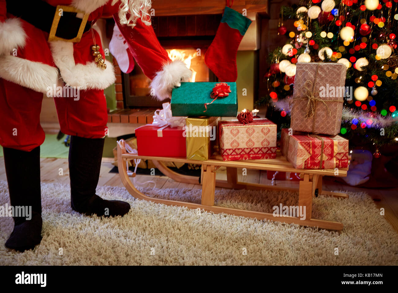 Babbo Natale porta i regali in casa accanto ad albero di natale Foto Stock