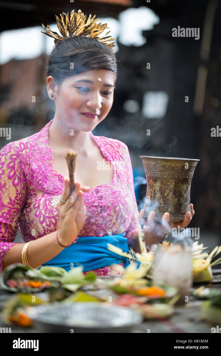 Giovane donna balinese pregando in tradizionali abiti cerimoniali Foto Stock