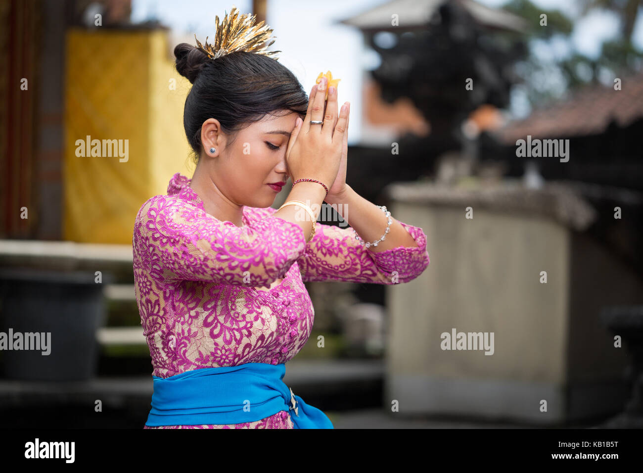 Ragazza balinese pregando ella inginocchiato con le mani giunte davanti al suo capo Foto Stock