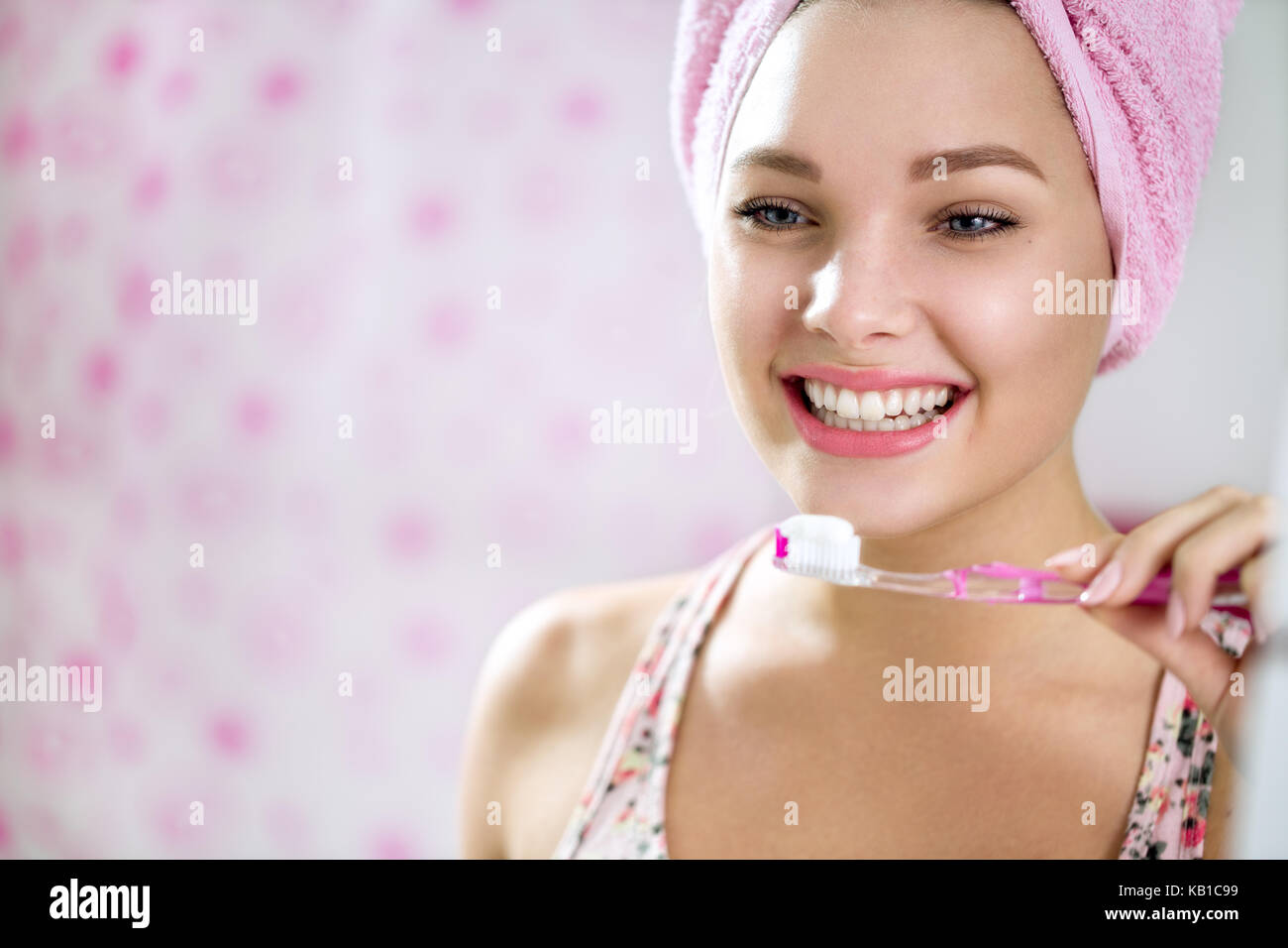 Sorridente ragazza di spazzolare i denti in bagno lato anteriore dello specchio retrovisore Foto Stock