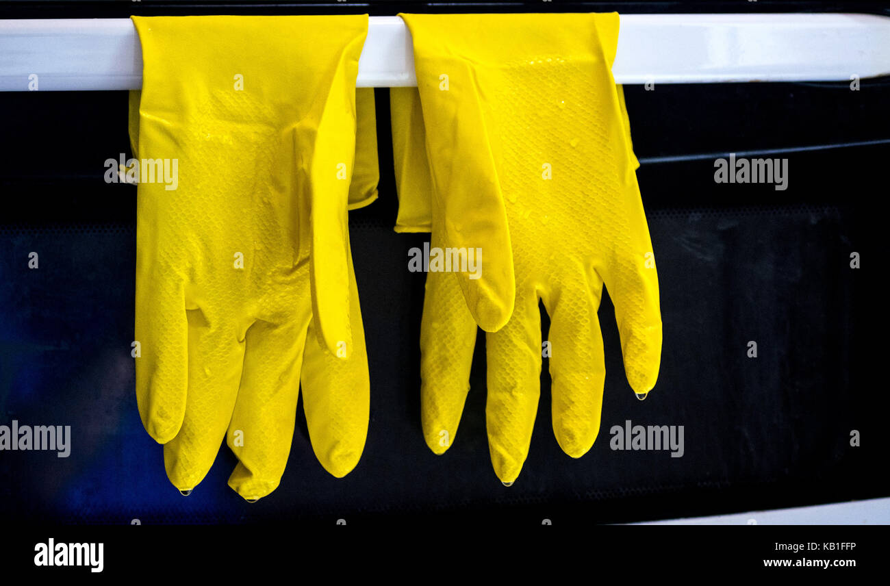 Gomma gialla cucina, lavastoviglie guanti, essiccamento dopo uso di fronte a un bianco e nero a forno Foto Stock