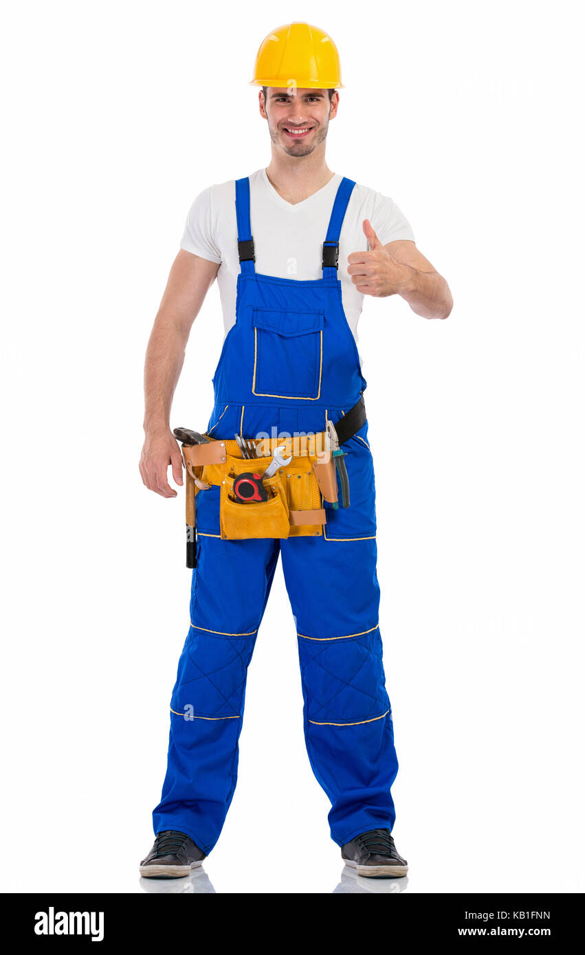 Sorridente giovane uomo in uniforme di costruzione che mostra pollice in alto Foto Stock