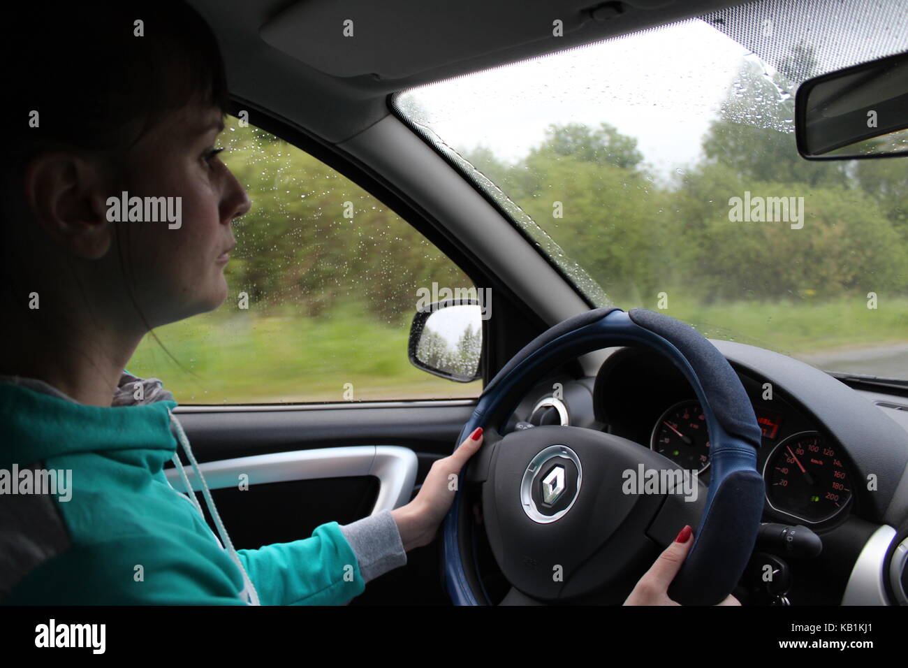 Una ragazza in un verde tuta sportiva aziona una vettura sotto la pioggia. Foto Stock