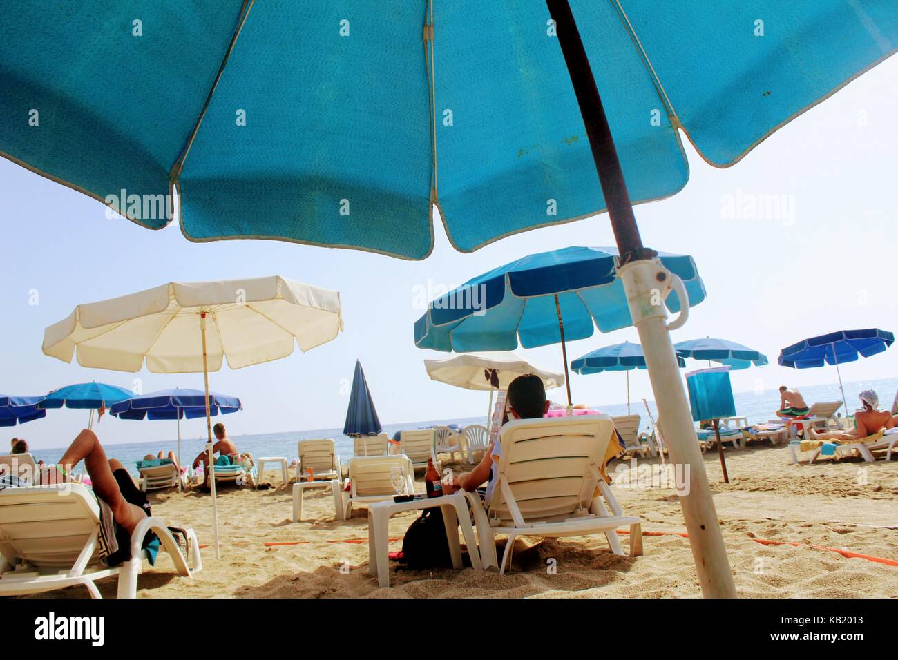 Luglio, 2017 - un uomo è in appoggio con una bottiglia di birra sdraiato su un lettino sulla spiaggia di cleopatra (Alanya, Turchia). Foto Stock