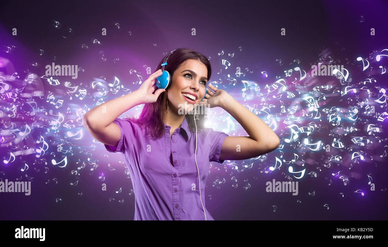 Piuttosto giovane donna con le cuffie per ascoltare musica, incandescente concetto note Foto Stock