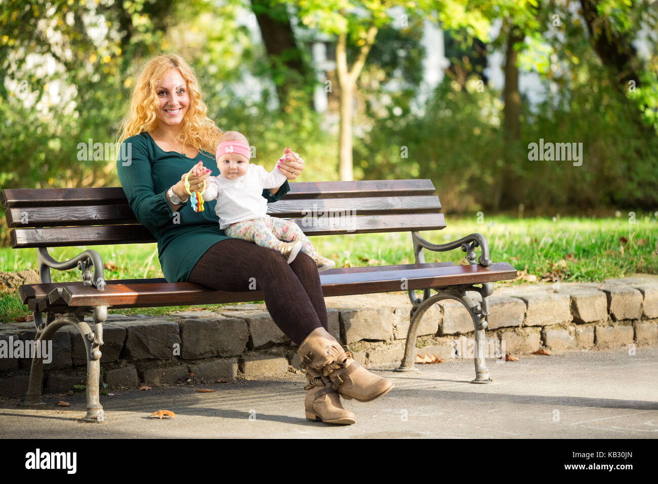 Madre seduta su una panchina nel parco con il bambino Foto Stock