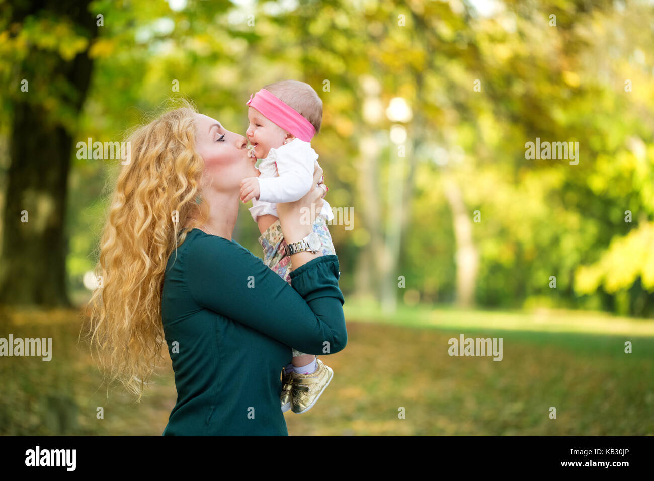 Felice famiglia allegra, il bambino e la madre baciare in natura outdoor Foto Stock