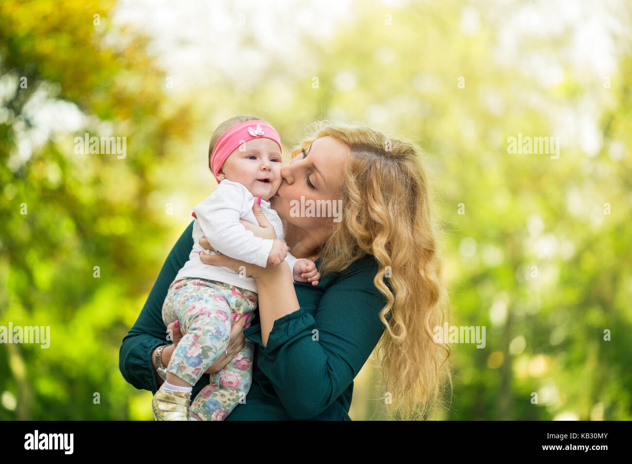 Giovane mamma baciando la sua figlia baby in posizione di parcheggio Foto Stock