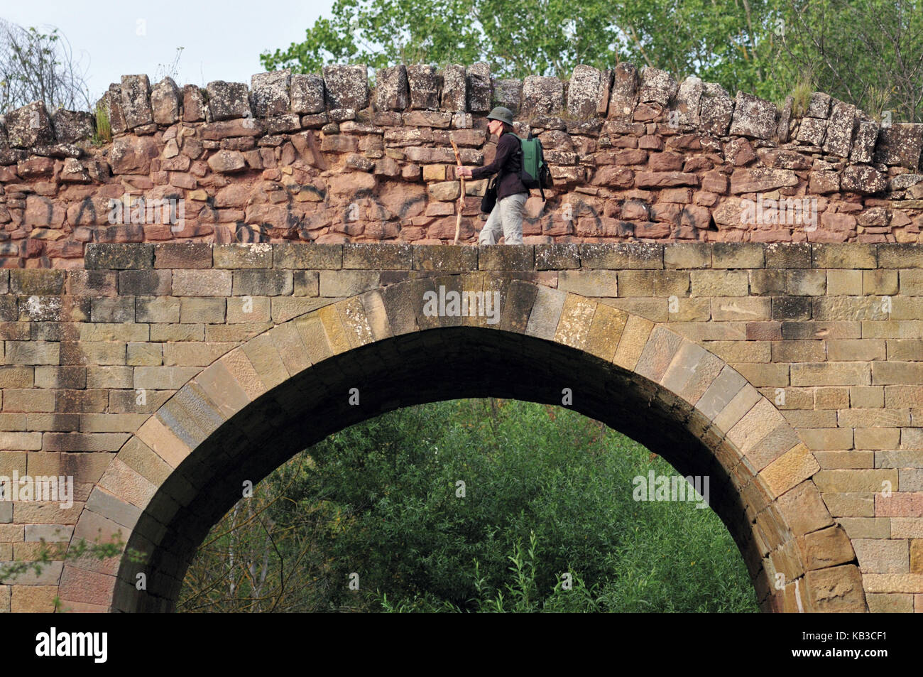 Spagna, Navarra, pellegrino giacobino attraversa il ponte romanico di Cirauqui, Foto Stock
