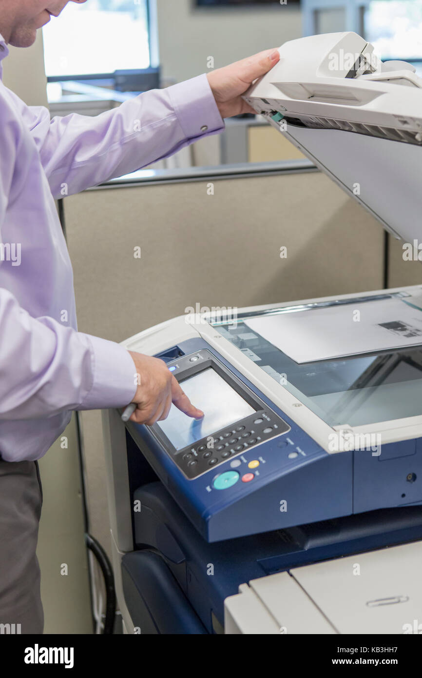 Executive maschio utilizzando la fotocopiatrice presso il centro di assistenza clienti del impianto di potenza elettrico Foto Stock