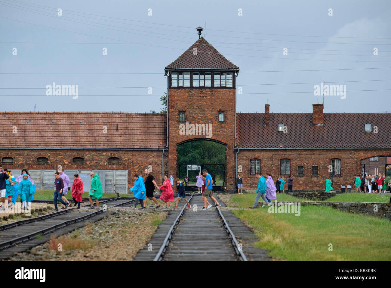 Turisti di passaggio davanti al cancello di ingresso alla II di Auschwitz Birkenau WWII campo di concentramento nazista, Polonia Foto Stock