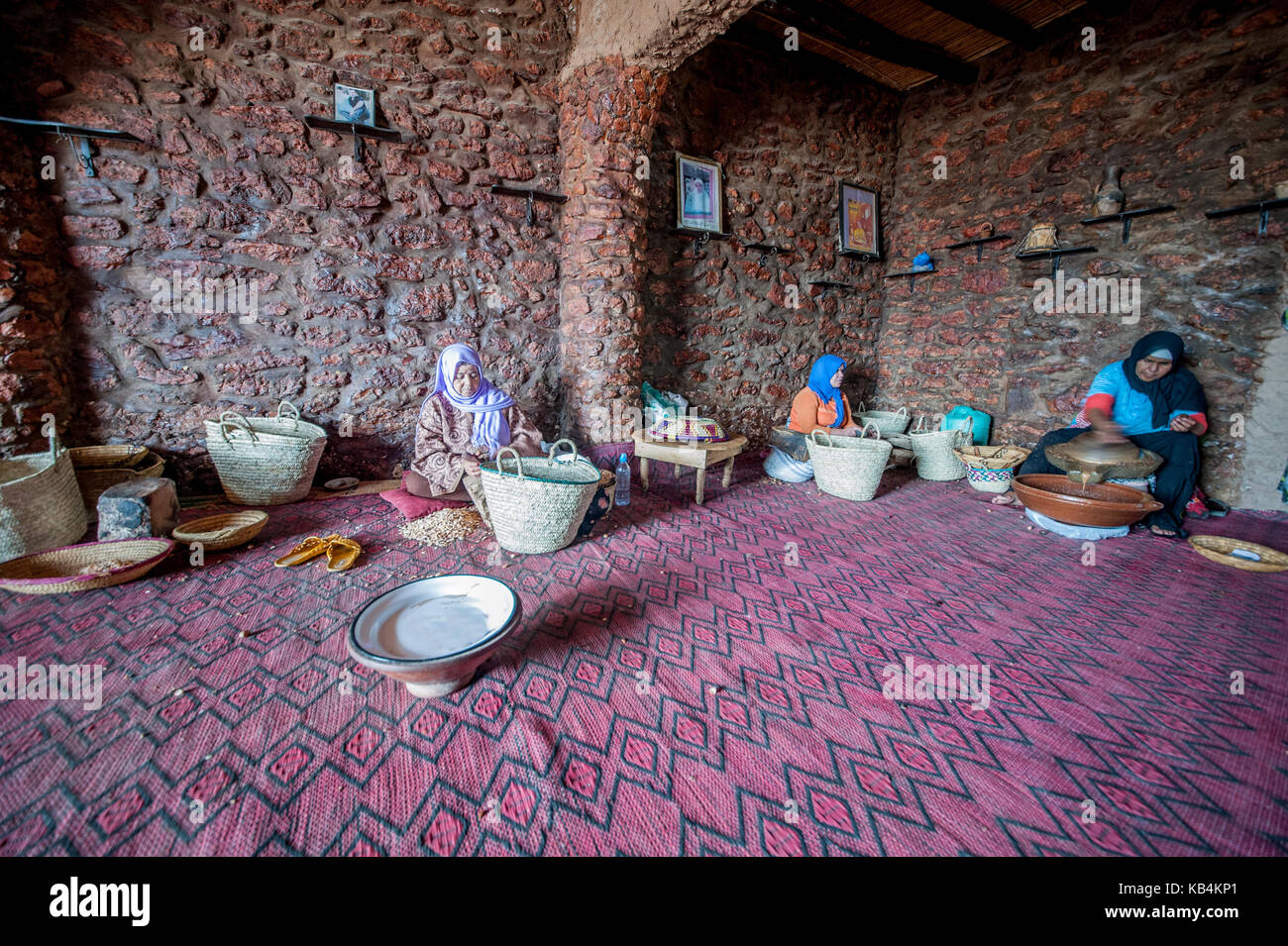 Olio di argan produzione. Una donna berbera rompere il guscio duro di un dado di argan con una pietra. Essaouira, Marocco Foto Stock