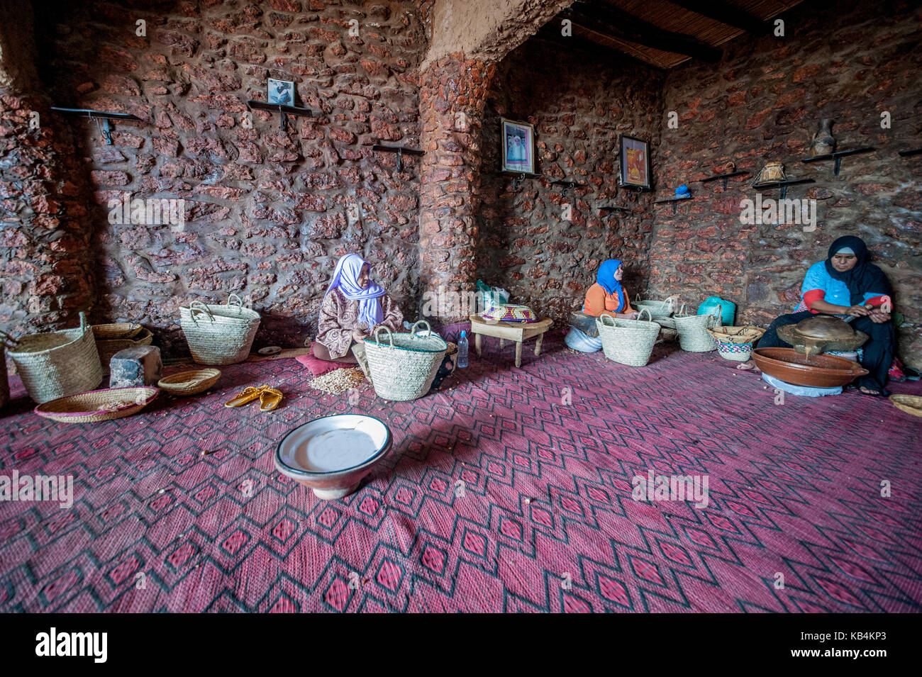 Olio di argan produzione. Una donna berbera rompere il guscio duro di un dado di argan con una pietra. Essaouira, Marocco Foto Stock