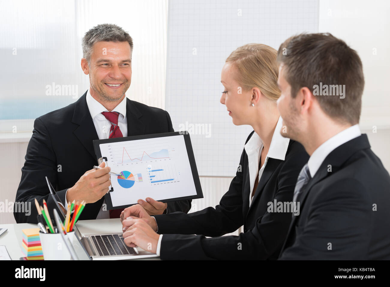 Imprenditore maturo che spiega il grafico ai suoi collaboratori in ufficio Foto Stock