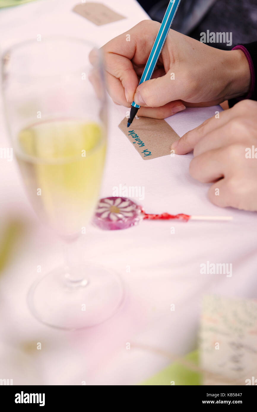 Addio al nubilato, partito donna scrive desideri su una nota, dettaglio, mani, tabella, lecca-lecca, coppa di champagne Foto Stock Addio al nubilato, partito donna scrive desideri su una nota, dettaglio, mani, tabella, lecca-lecca, coppa di champagne Foto Stock