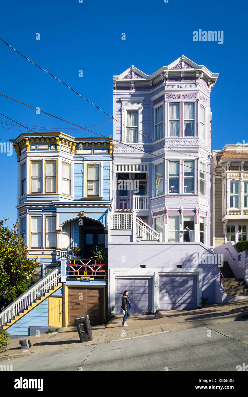 Una ragazza cammina su Sanchez Street (nota architettura Victorian-Italianate) nel quartiere Castro di San Francisco, California. Foto Stock