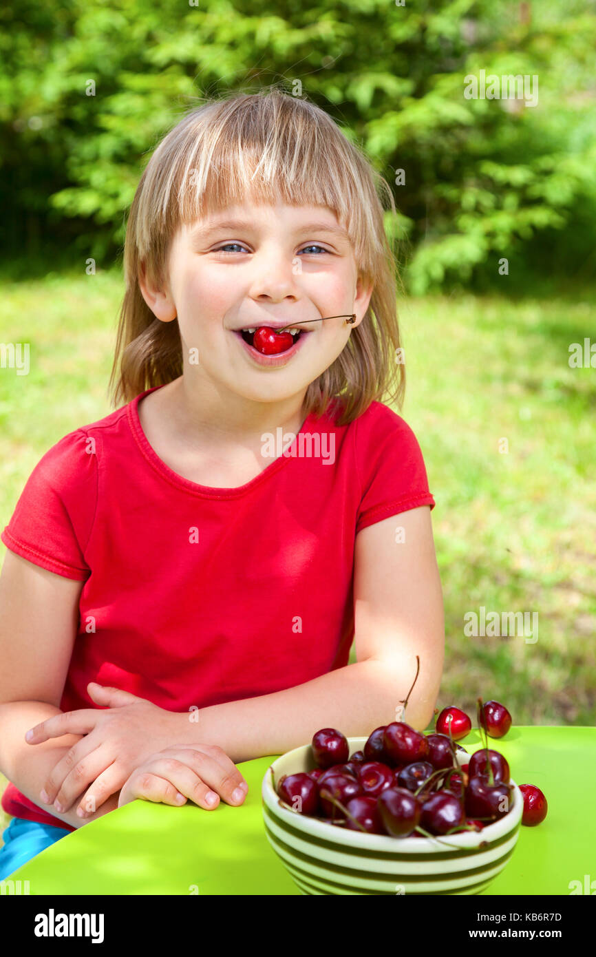 Carino bambina mangiare ciliegio dolce all'aperto Foto Stock