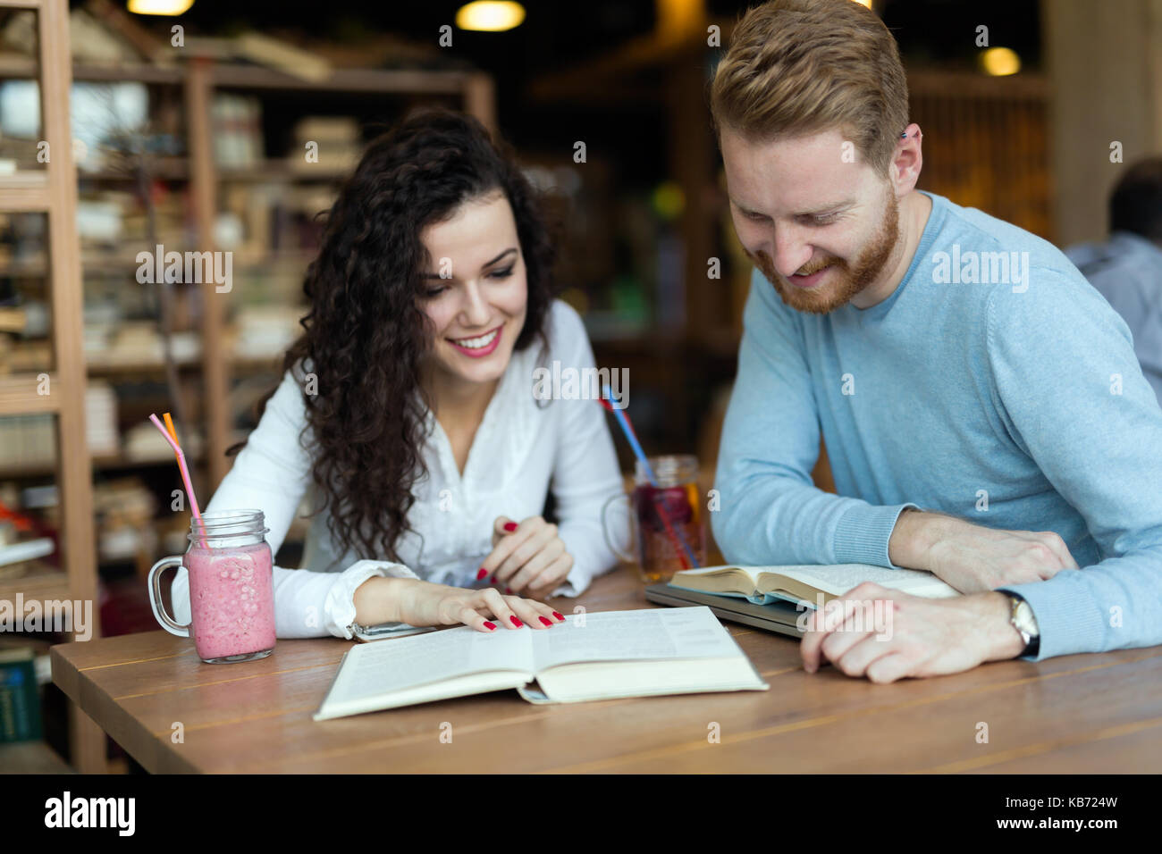 I giovani studenti di trascorrere del tempo in un coffee shop libri di lettura Foto Stock
