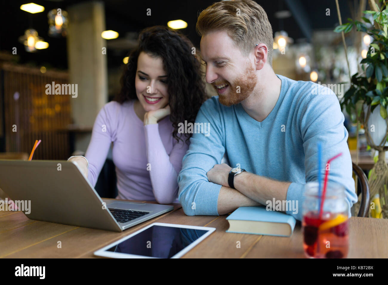 Coppia felice di trascorrere del tempo presso la caffetteria lavorando sul computer portatile Foto Stock
