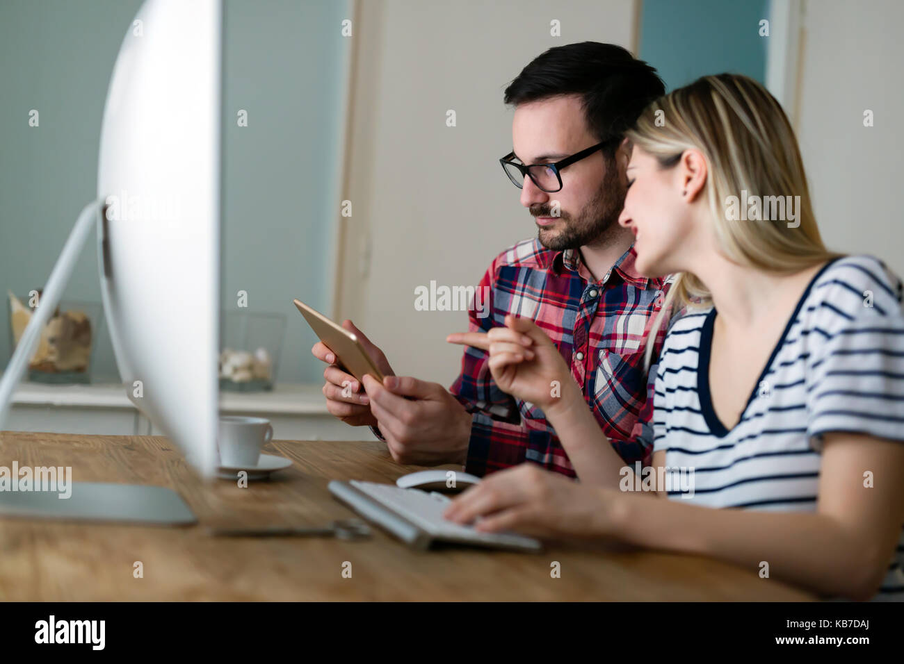 Attraente di giovani progettisti che lavorano insieme da casa Foto Stock