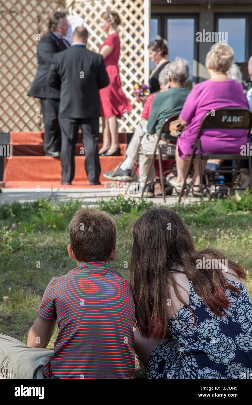 Finlandia, minnesota - un ragazzo e una ragazza guarda un paio di sposarsi a un matrimonio all'aperto. Foto Stock