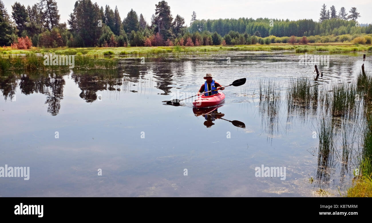 L'uomo canoa kayak su un piccolo lago di montagna nel centro di Oregon Foto Stock