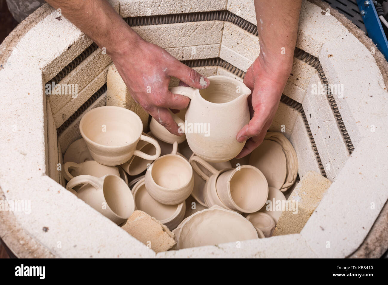 Ceramiche, workshop, arte ceramica concetto - close-up sul forno elettrico  per la tostatura di argilla crudi prodotti, maschio mettendo le mani la  caraffa nel forno, s Foto stock - Alamy