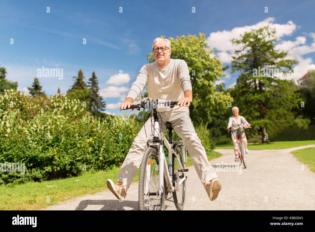 Felice coppia senior equitazione biciclette al summer park Foto Stock