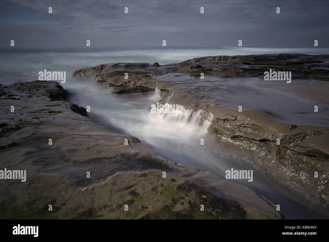 Una lunga esposizione la jolla seascape del rocky la jolla costa a san Diego in California con una nebbiosa cascata di marea e scuro moody sky. Foto Stock