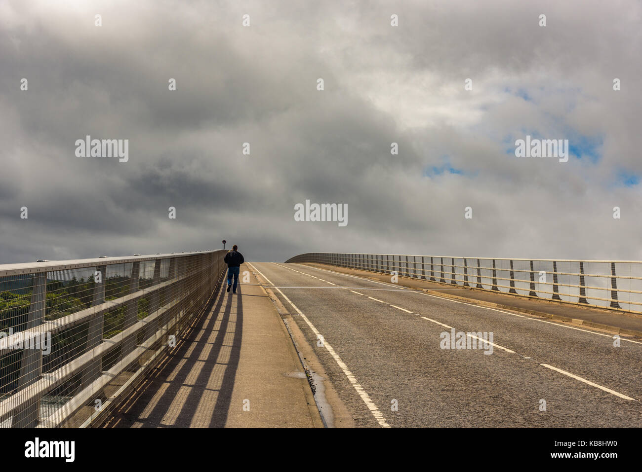 Un uomo adulto a piedi da sola sulla Skye Bridge in Scozia, Regno Unito Foto Stock