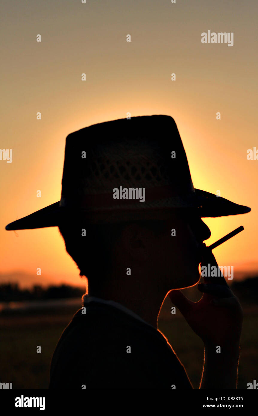 Silhouette di un cowboy con cappello e sigaretta Foto Stock