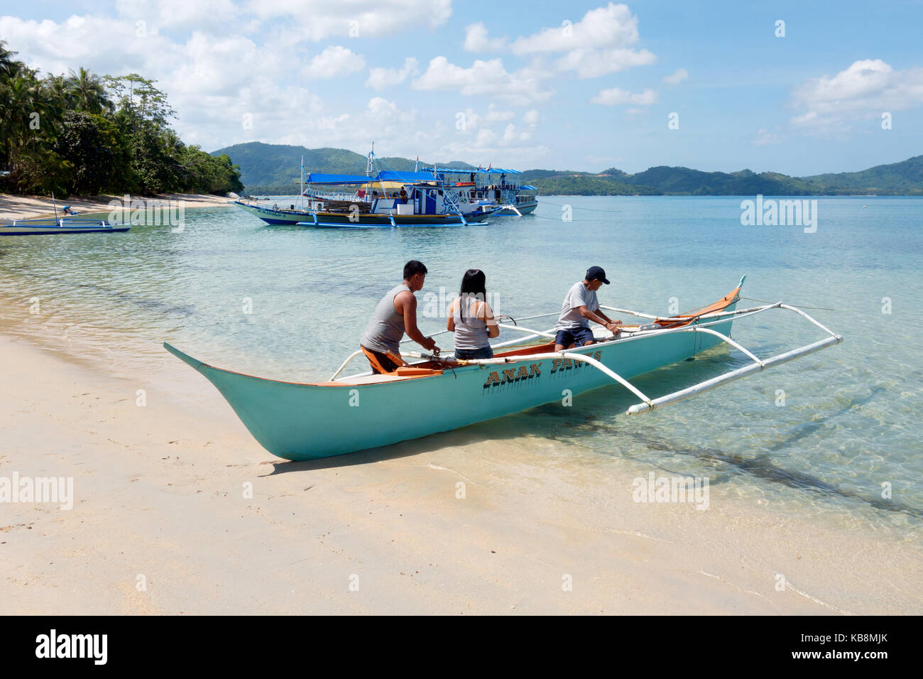 Palawan Filippine - gente locale che spinge fuori una barca, El Nido, Palawan, Filippine Asia Foto Stock