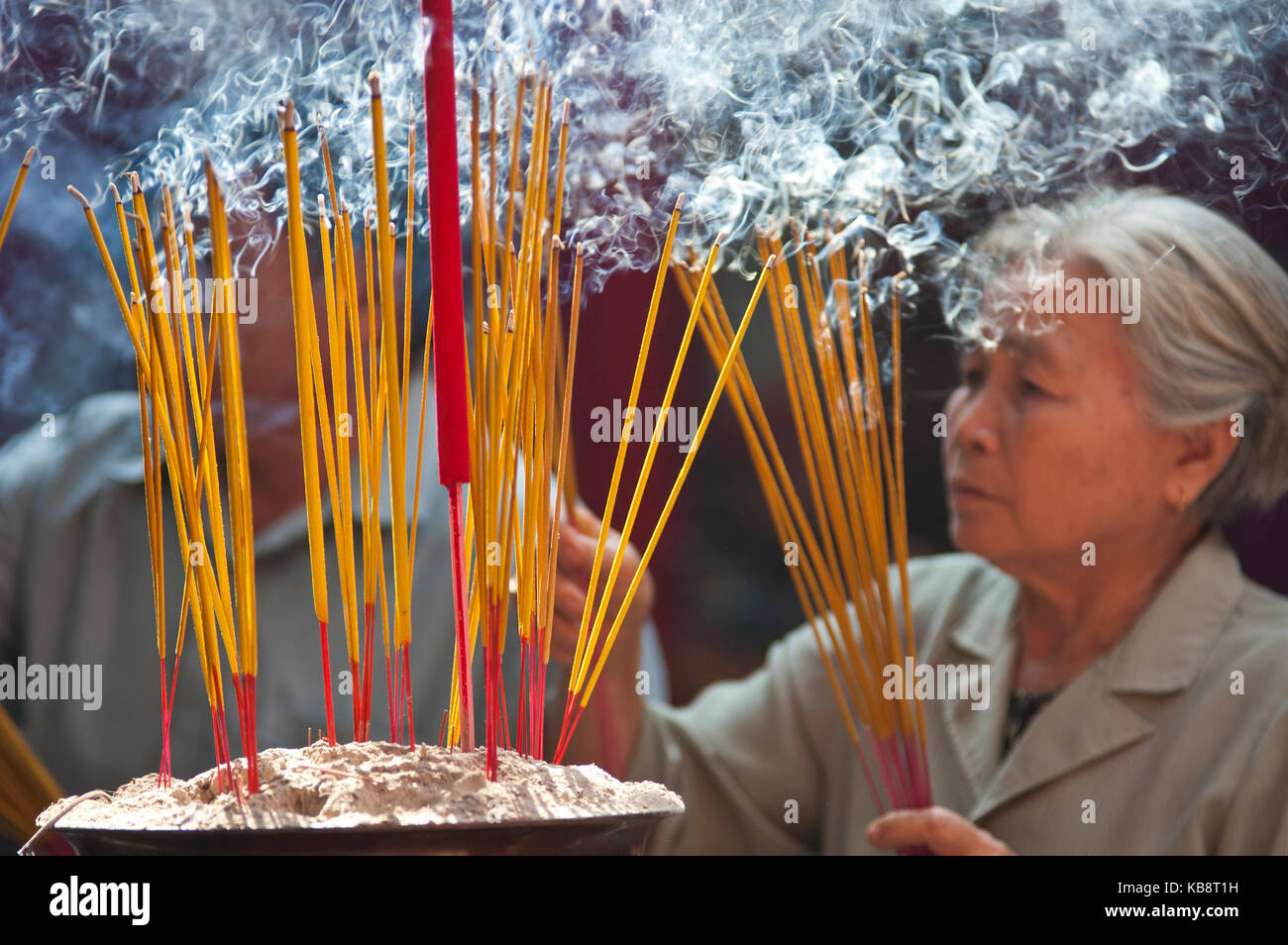 La città di Ho Chi Minh, Vietnam - febbraio, 6 : una donna senior luoghi fumatori bastoncini di incenso in un'urna all'interno del Tempio Thien Hau nella Chinatown di ho chi mi Foto Stock