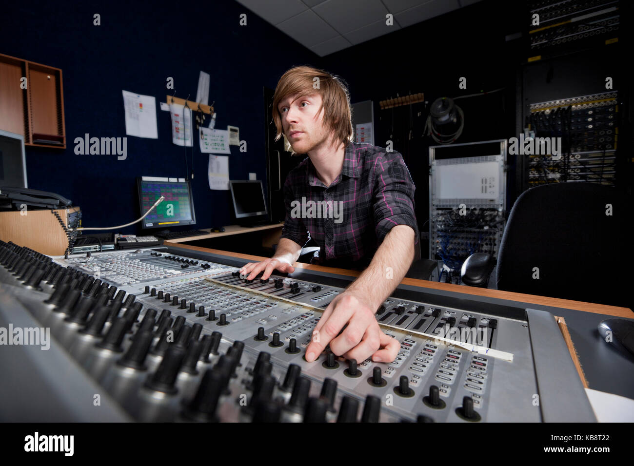 Uomo che utilizza un suono miscelazione scrivania in uno studio di registrazione. Foto Stock
