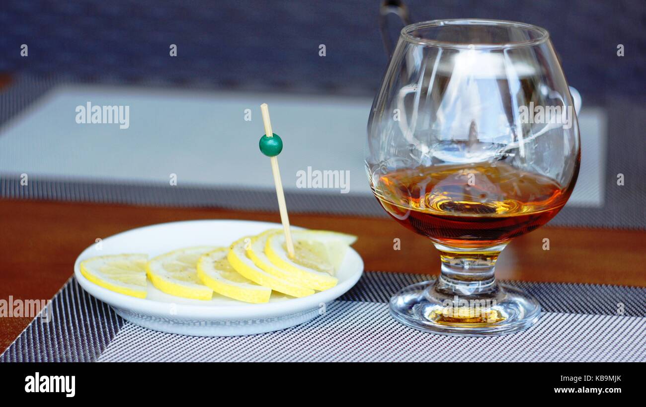 Un bicchiere di brandy con fettine di limone e cosparsi con sale e pepe. Questo è il miglior rimedio per il mal di testa. Foto Stock